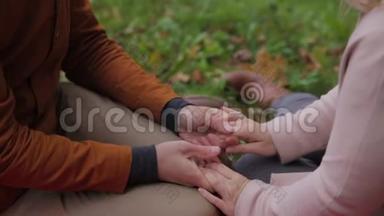 年轻夫妇<strong>坐在</strong>一个夏天的<strong>公园里</strong>，在一条格子的野餐毯上野餐。 <strong>公园里</strong>的一对